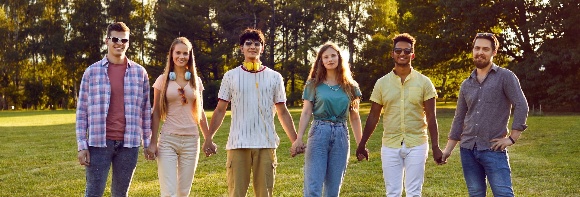 Group of people holding hands in a park, smiling. Group of people holding hands in a park, smiling.