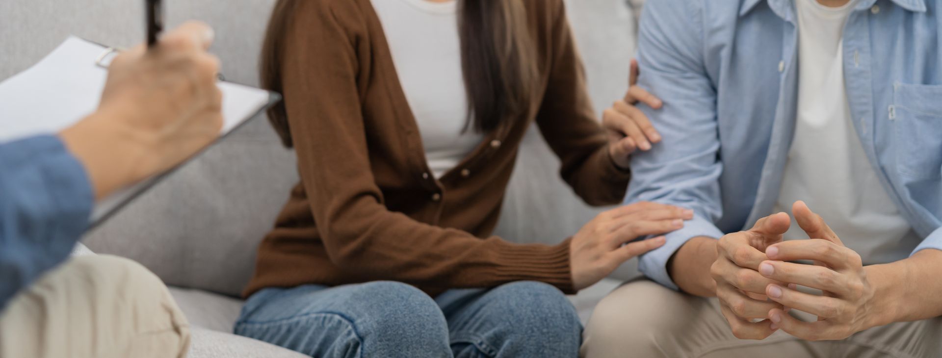 Couple in therapy, one comforting the other with a hand on the arm. Therapist taking notes. Couple in therapy, one comforting the other with a hand on the arm. Therapist taking notes.