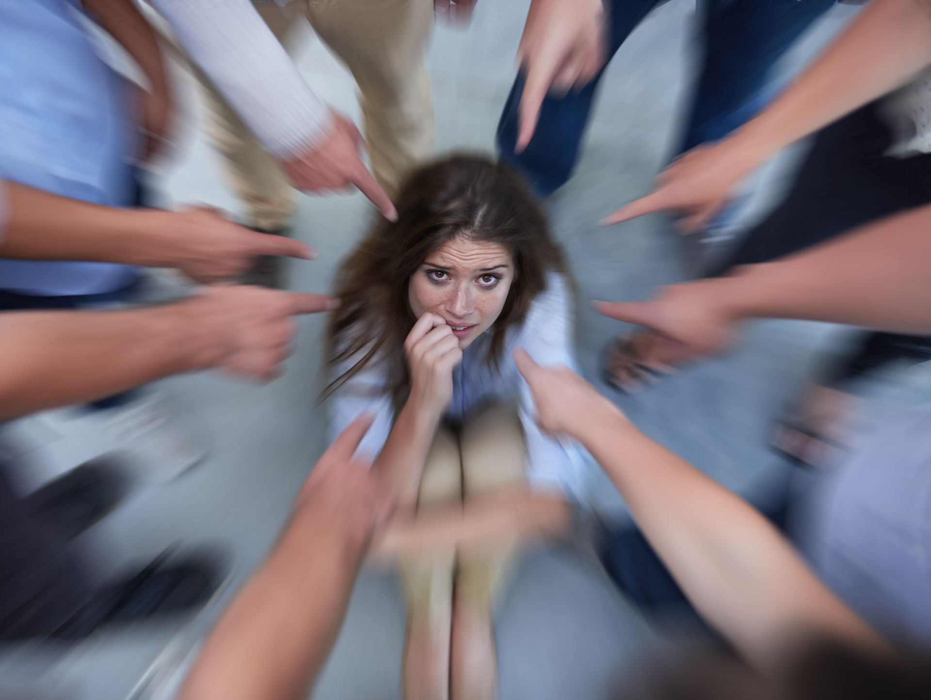 Woman looks frightened, surrounded by blurred hands pointing towards her. Woman looks frightened, surrounded by blurred hands pointing towards her.