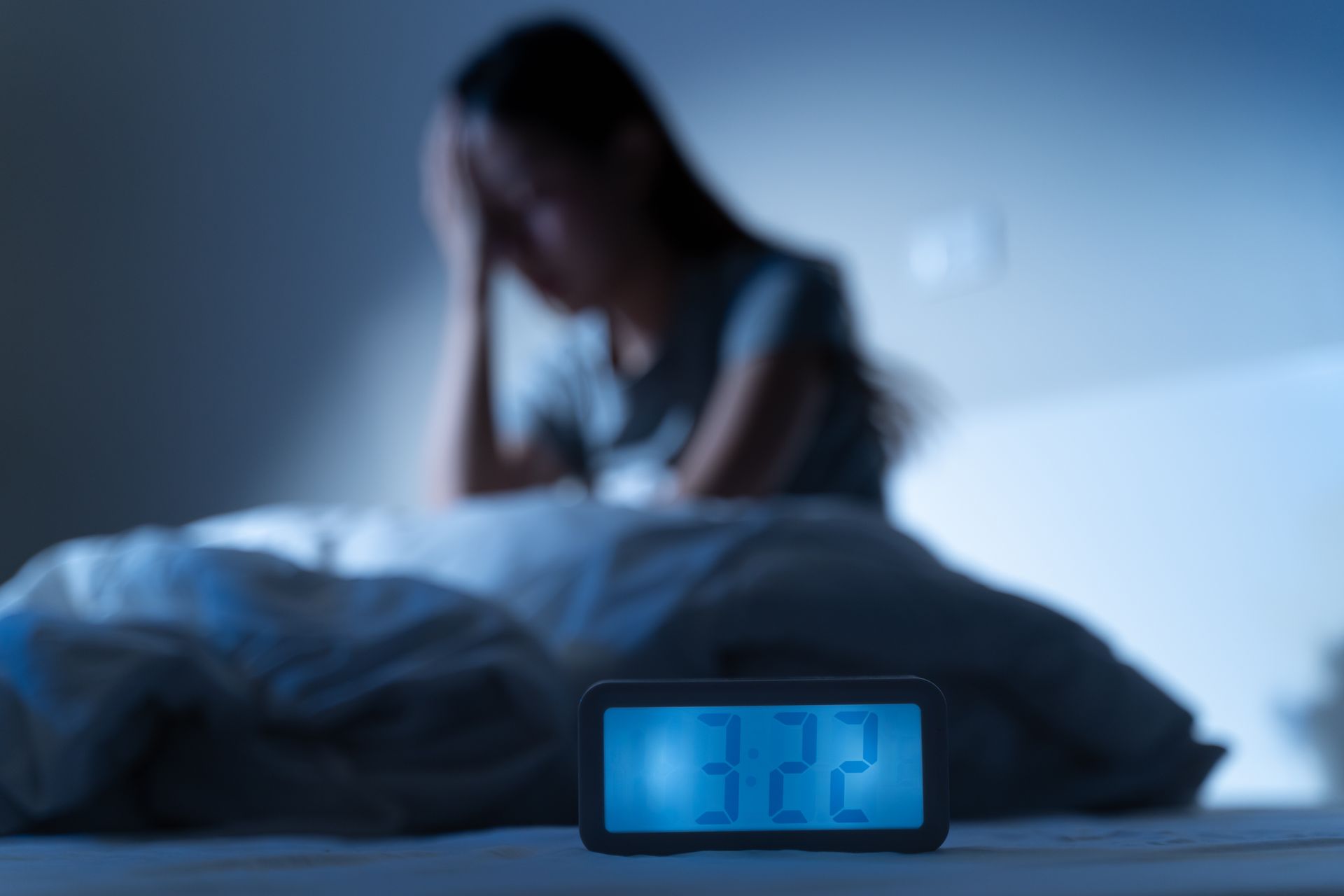 Woman in bed with digital clock showing 3:22 AM, looking stressed. Dark blue and white setting. Woman in bed with digital clock showing 3:22 AM, looking stressed. Dark blue and white setting.