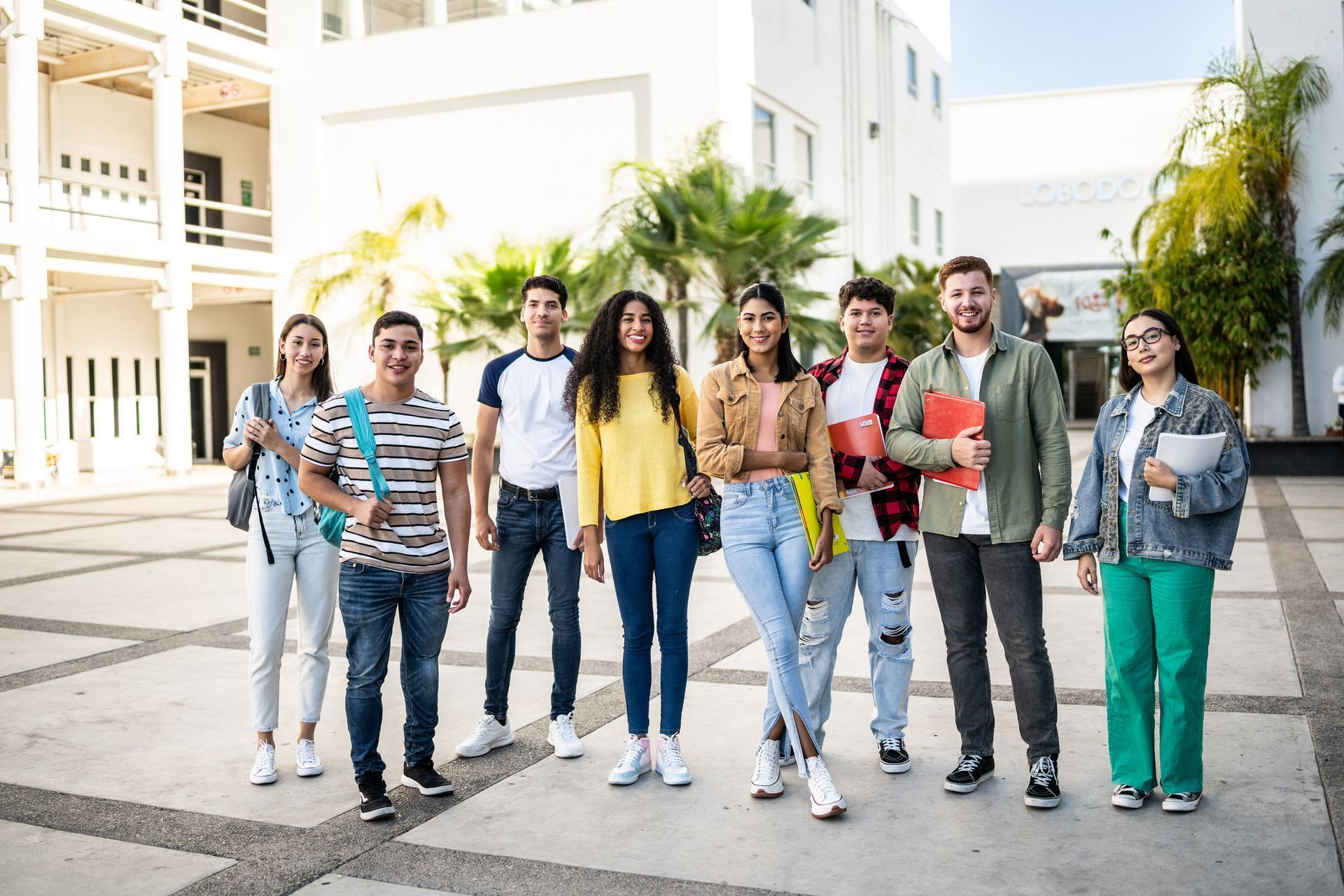 Group of students standing together on a campus, smiling. Buildings in the background. Group of students standing together on a campus, smiling. Buildings in the background.