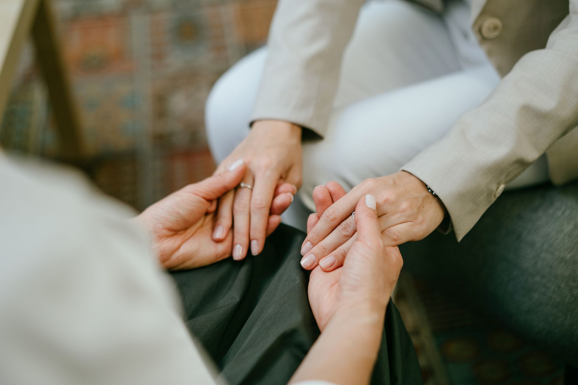Hands holding in supportive gesture, likely in a counseling session. Hands holding in supportive gesture, likely in a counseling session.