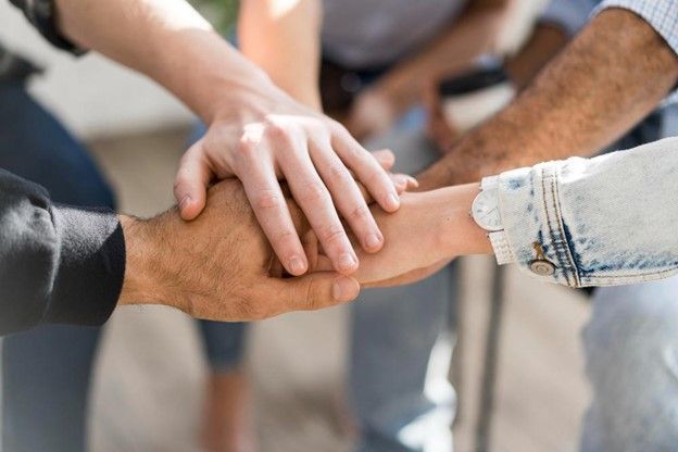 Hands clasped together in a team huddle, symbolizing unity and collaboration.