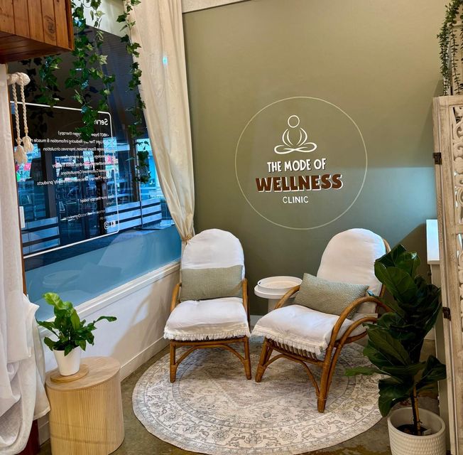 Two chairs on a rug in a wellness clinic waiting area with a sign that reads "The Node of Wellness Clinic."