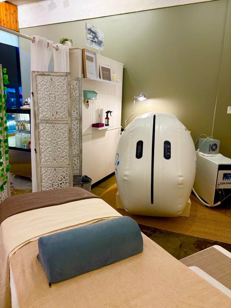 Massage table and hyperbaric chamber in a treatment room.