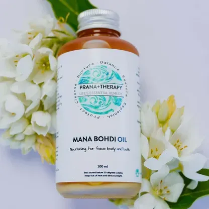 Bottle of Mana Bohdi Oil, surrounded by white flowers. Label reads
