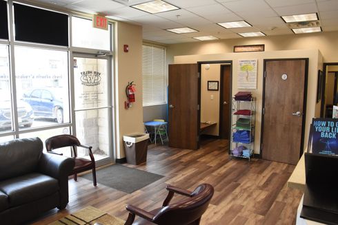 Salon waiting area with leather chairs, wood floor, and three private rooms.