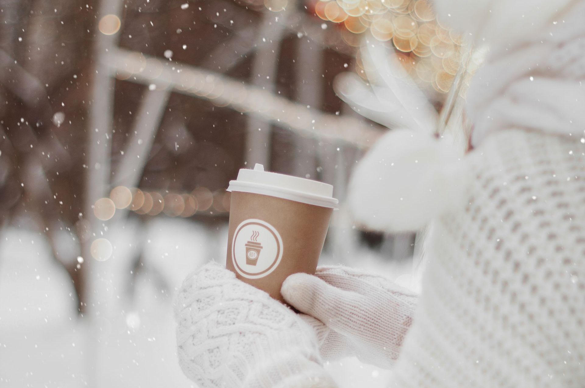 A person is holding a cup of coffee in the snow.