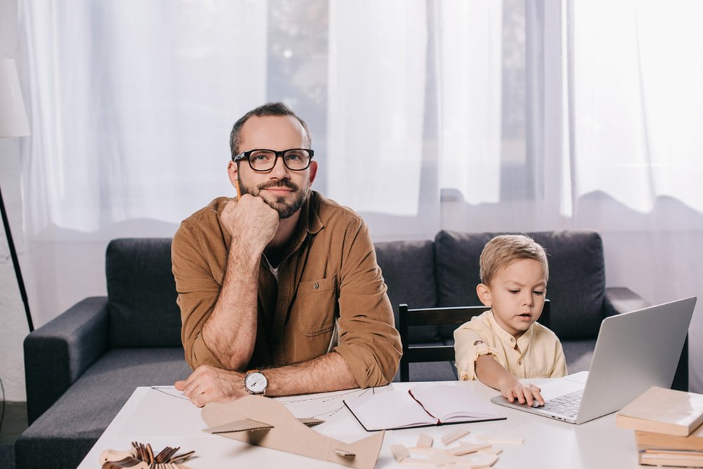 a father and son with a laptop consider hiring air duct cleaning company