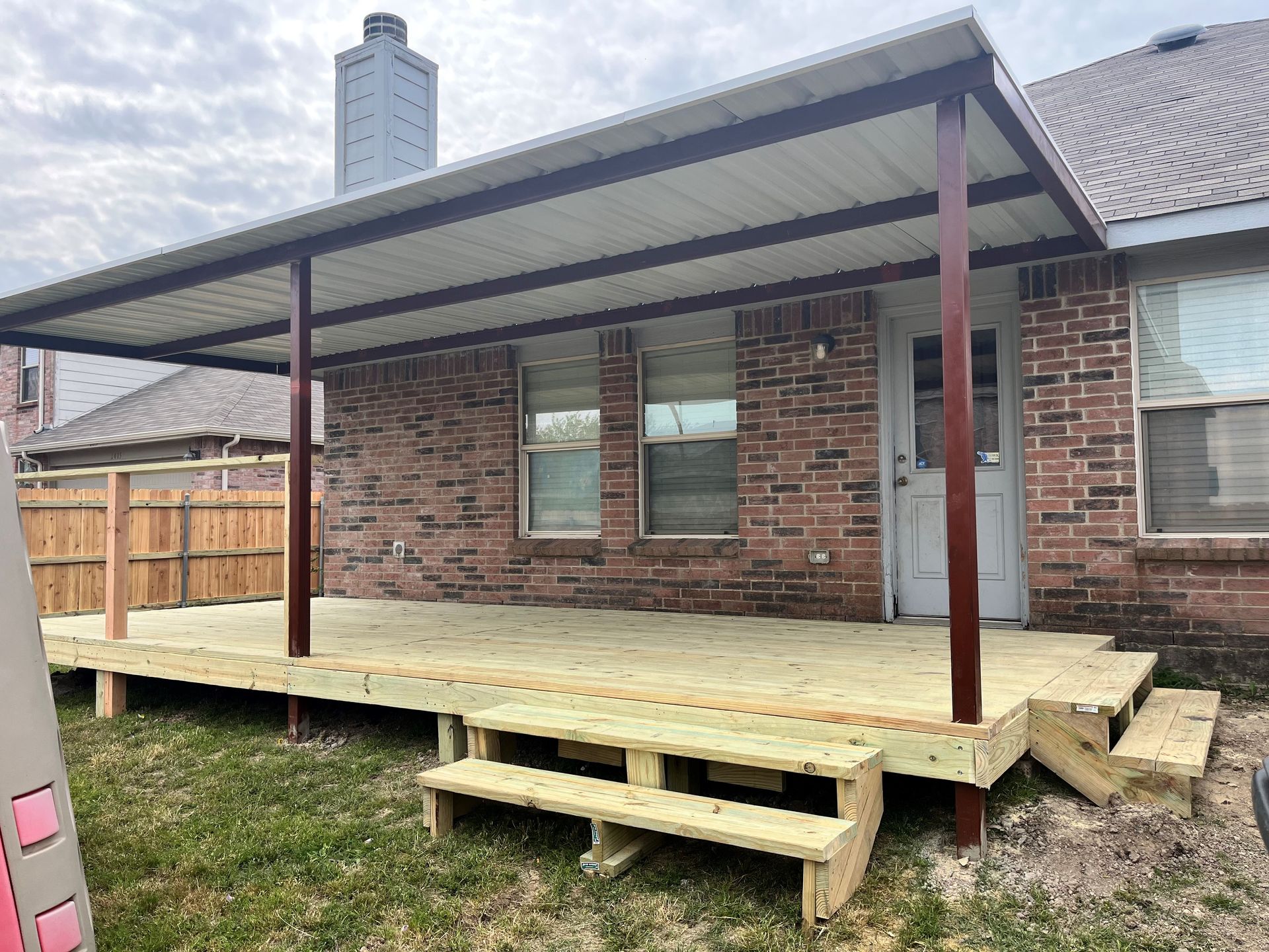 A large awning is covering a patio with a couch and chairs.
