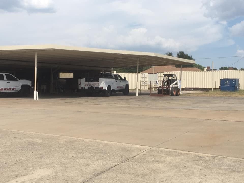 A car is parked under a carport in front of a brick house.