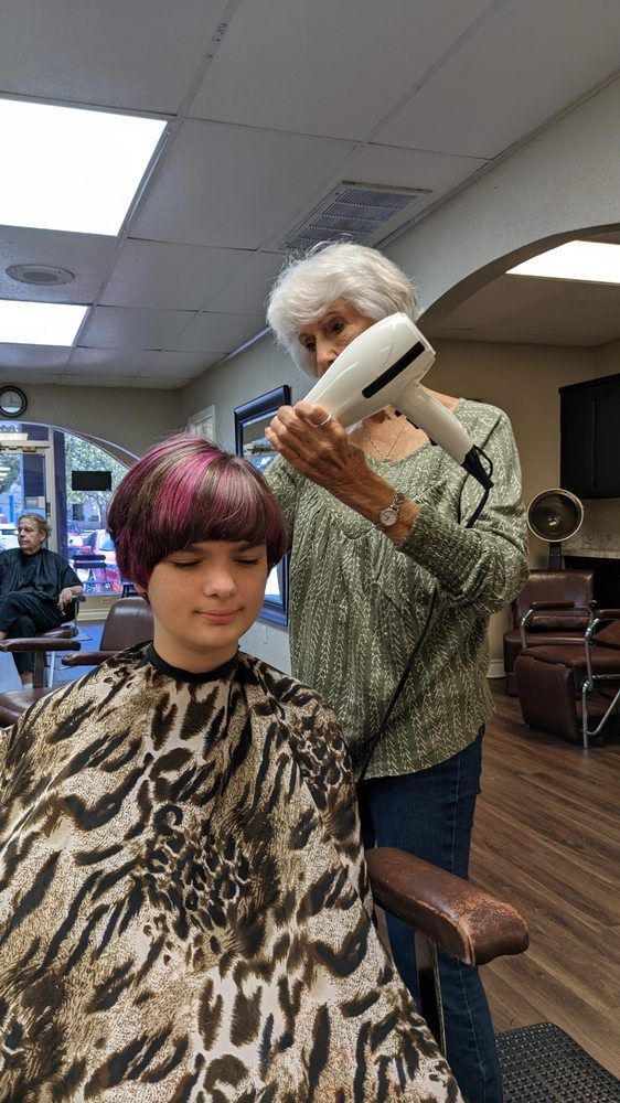 A woman is blow drying a young girl 's hair in a salon.