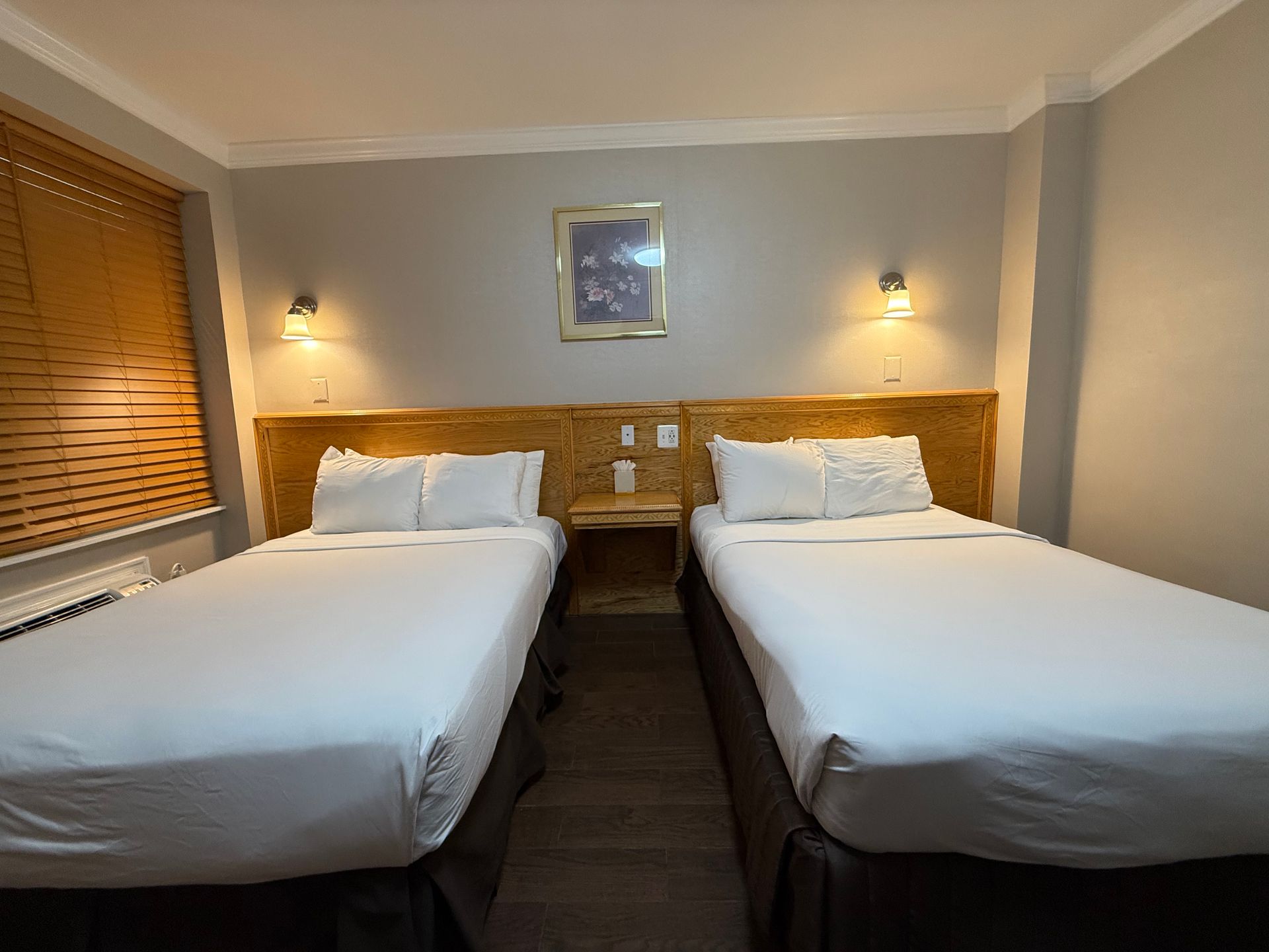 Two twin beds in a hotel room, with a nightstand between them.