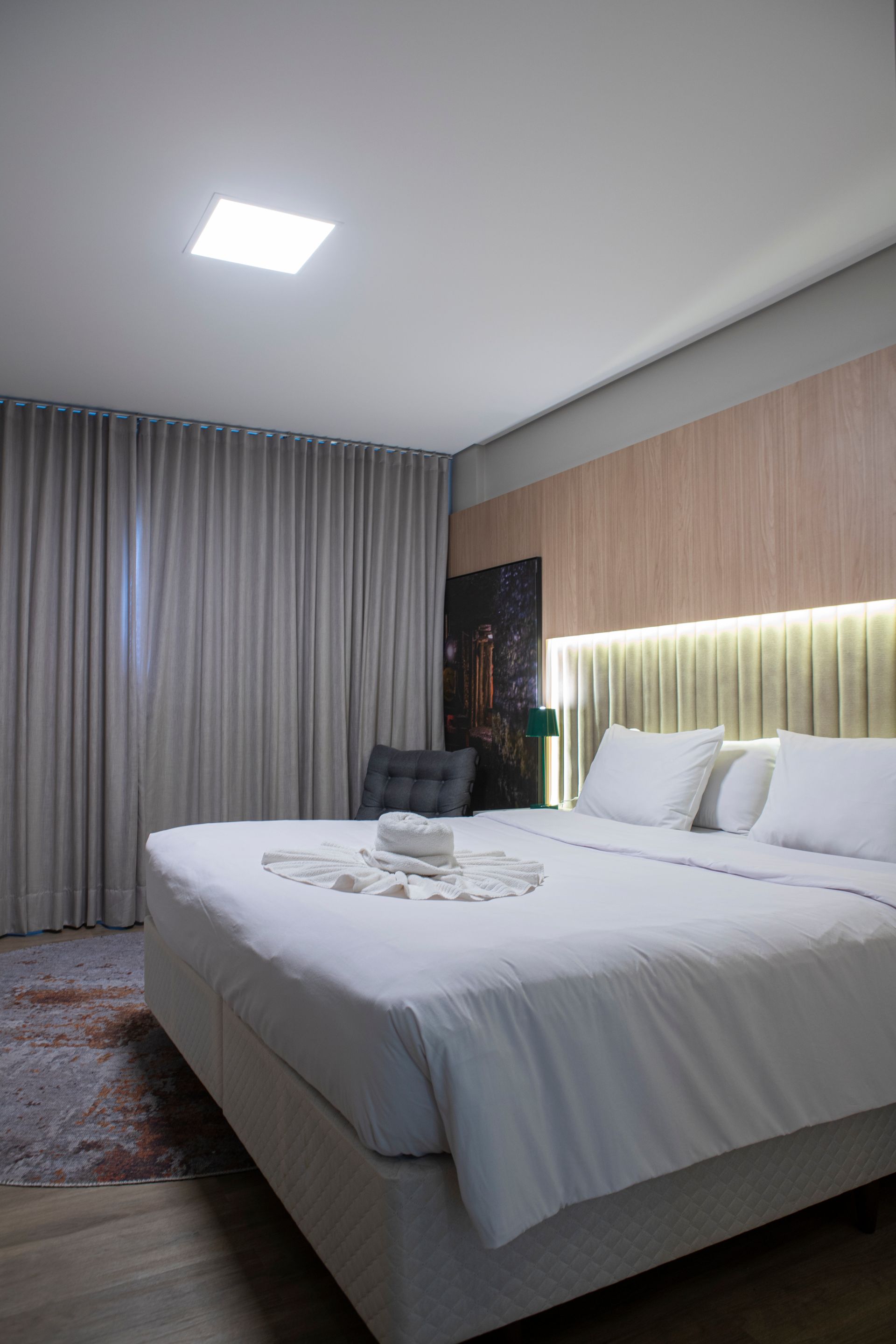 Um quarto de hotel com uma cama king size e uma cadeira.