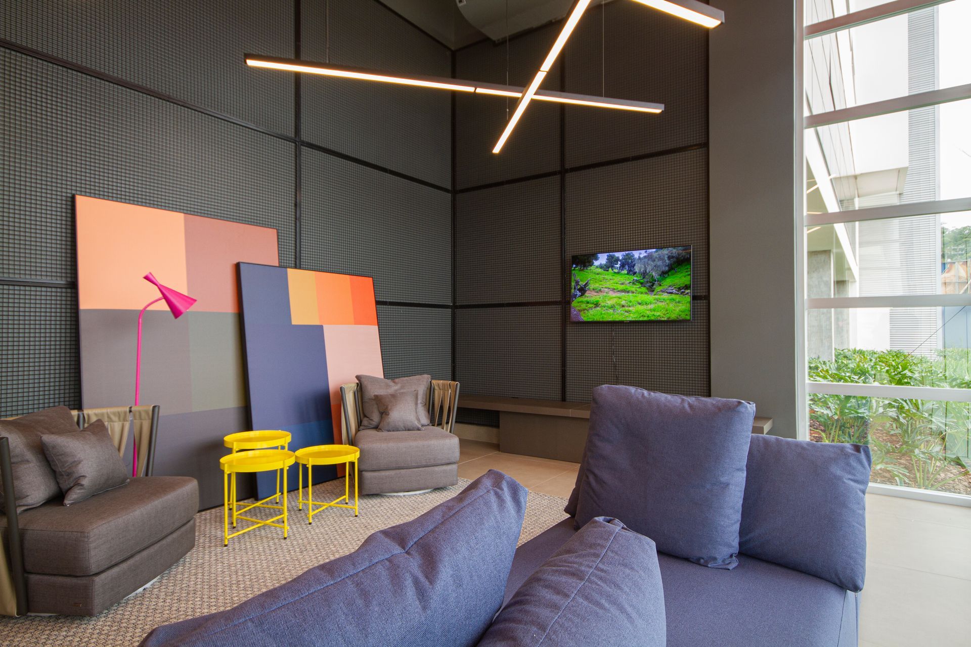 Uma sala de estar com um sofá, cadeiras e uma televisão.