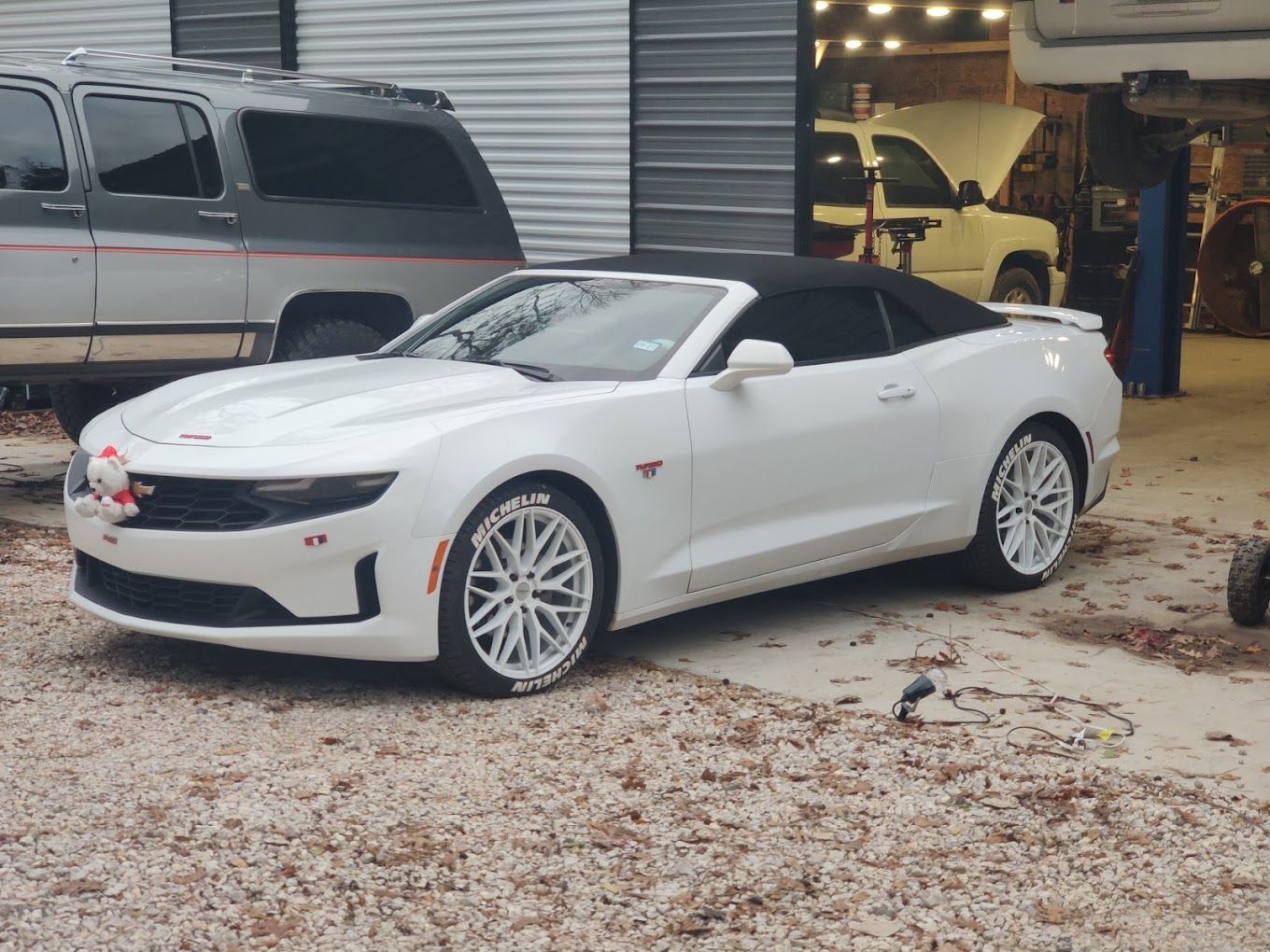 White convertible Camaro parked outside a garage; white rims, black soft top. | Freedom Auto Repair