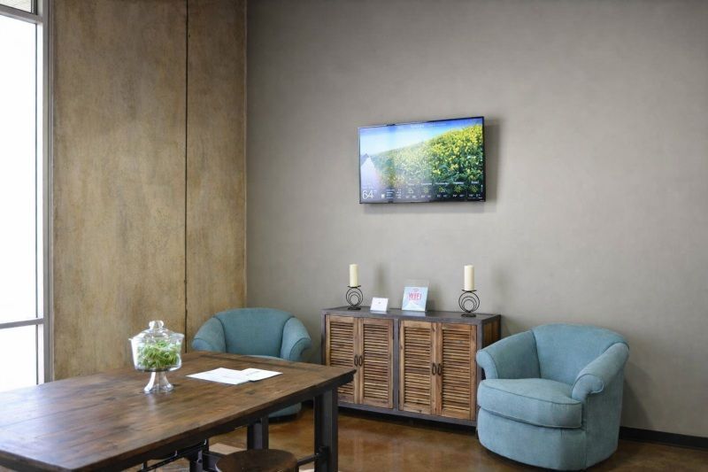 Modern waiting area for Direct Cremation Midwest City, OK with blue chairs, wood table, cabinet and wall TV