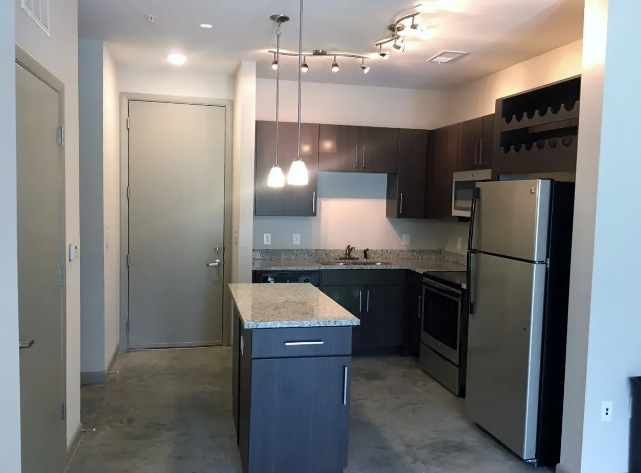 Modern apartment kitchen with stainless steel appliances and granite countertops.