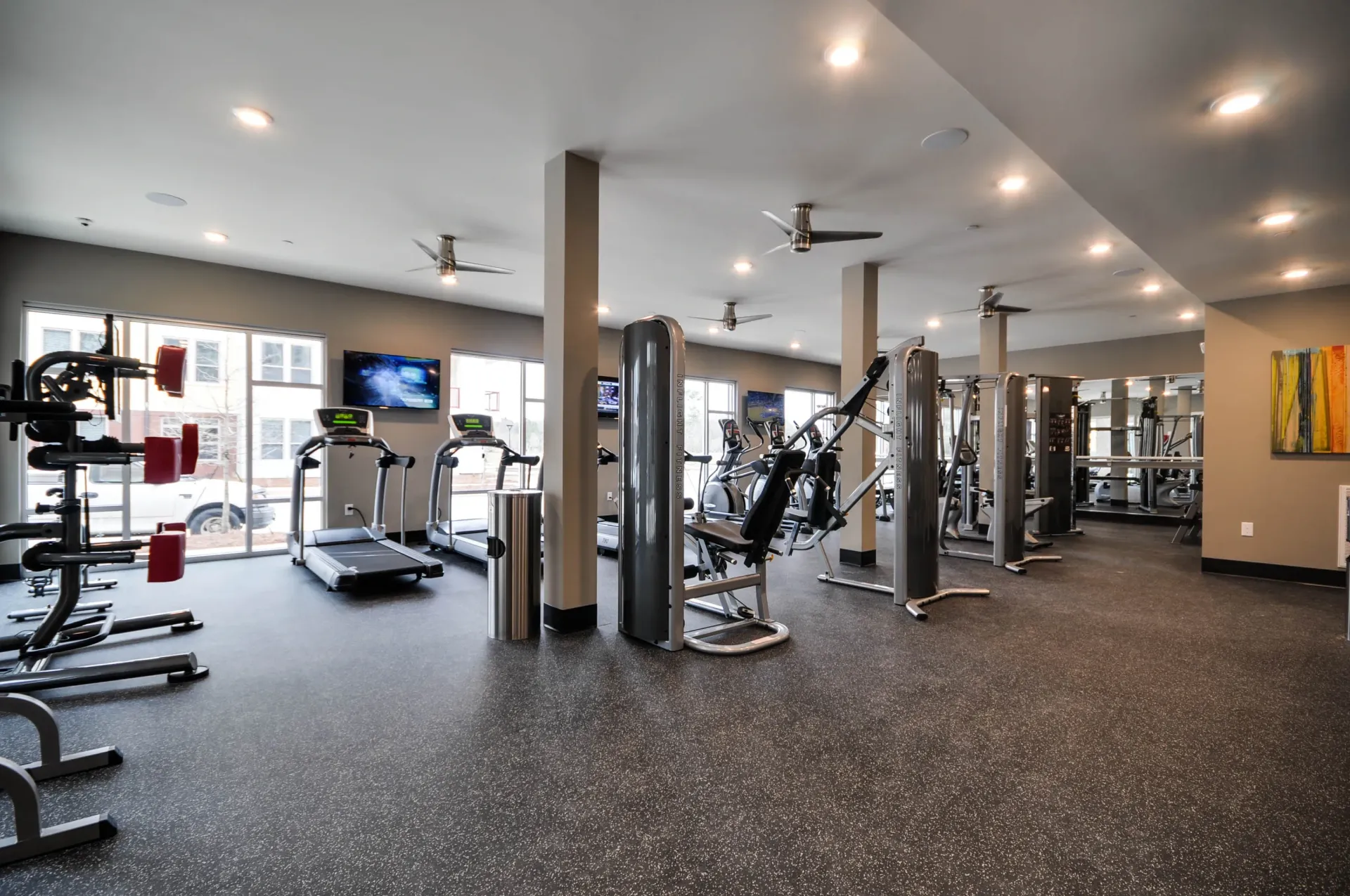 Modern gym with treadmills, weight machines, and large windows.