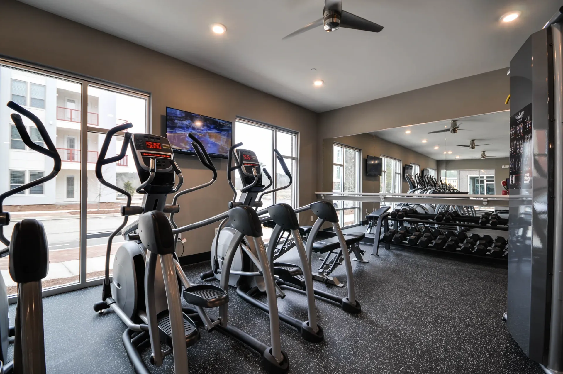 Elliptical machines and free weights in a modern apartment gym.