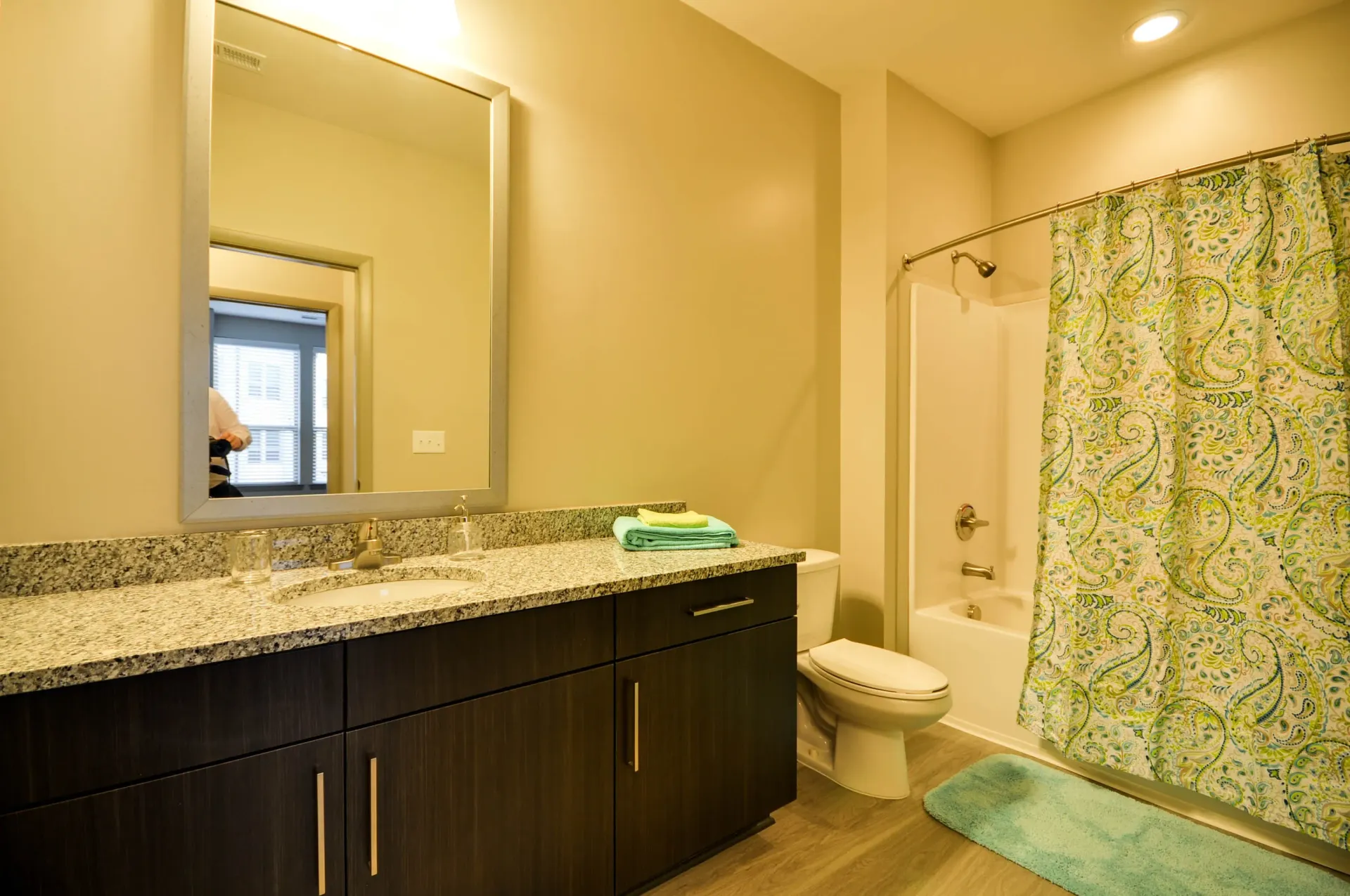 Modern bathroom with granite countertop, vanity, and shower-tub combo.