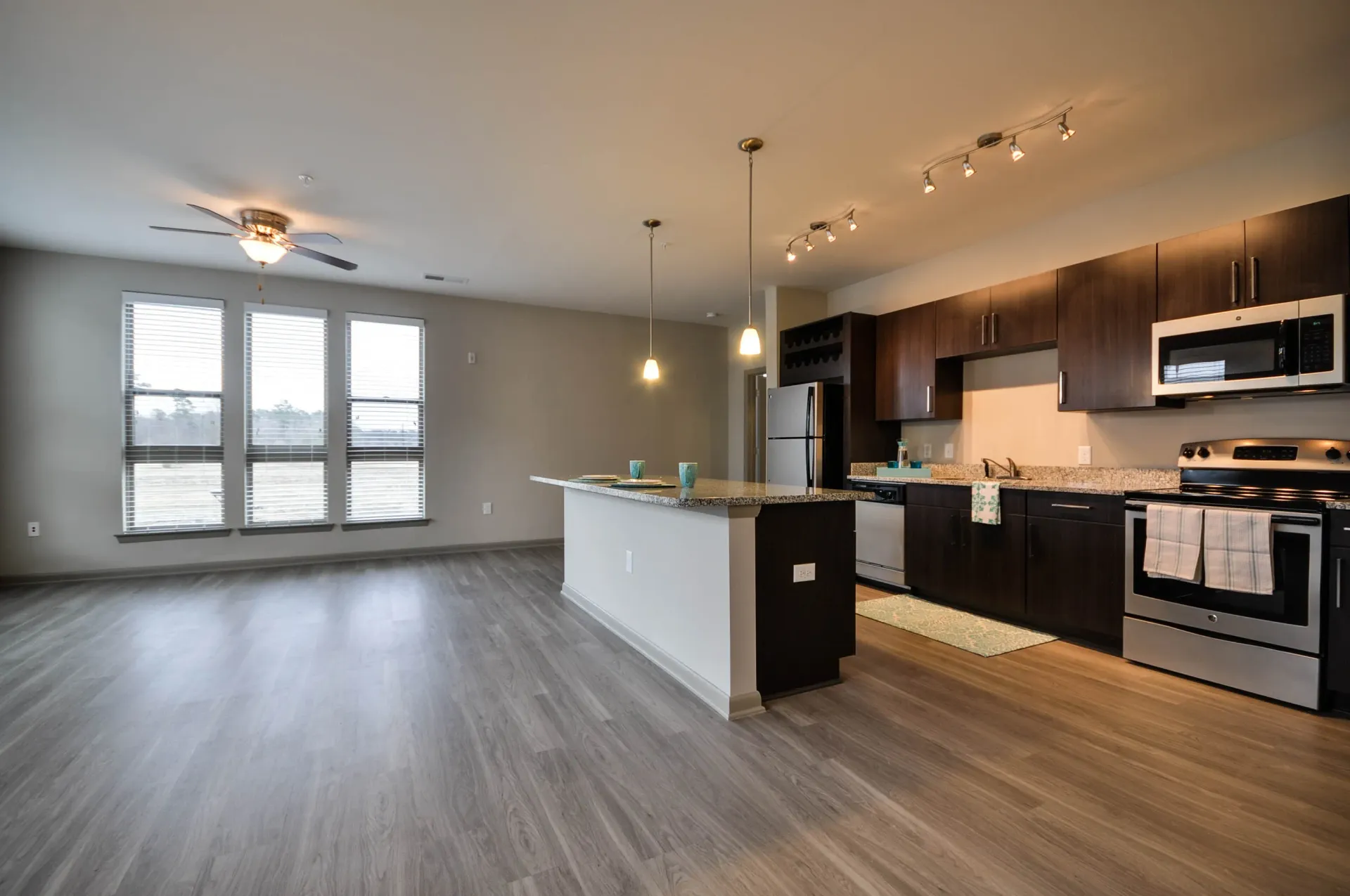 Modern kitchen with island, dark wood cabinets, stainless steel appliances, and large windows.