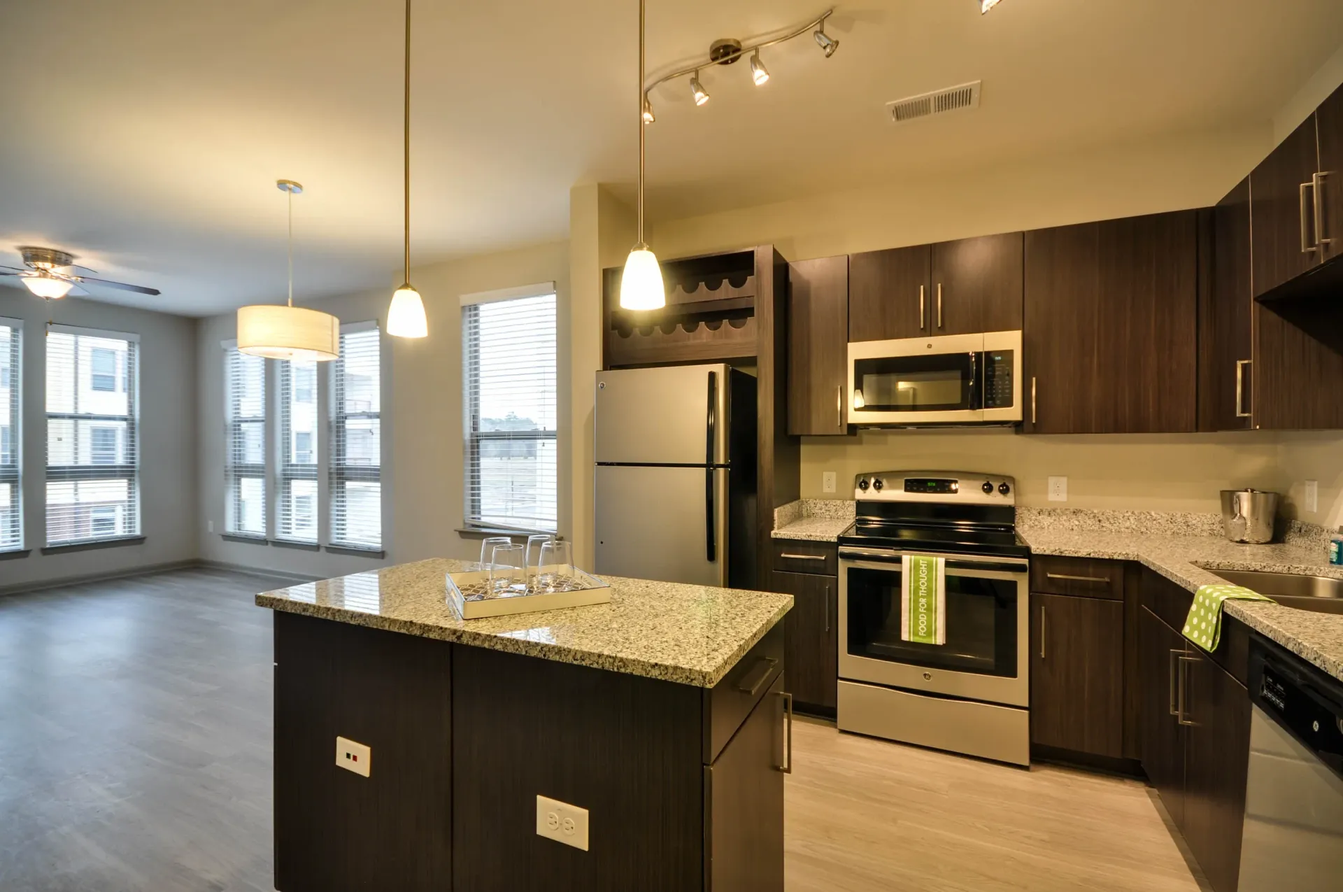 Modern kitchen with dark wood cabinets, granite countertops, stainless steel appliances, and an island.