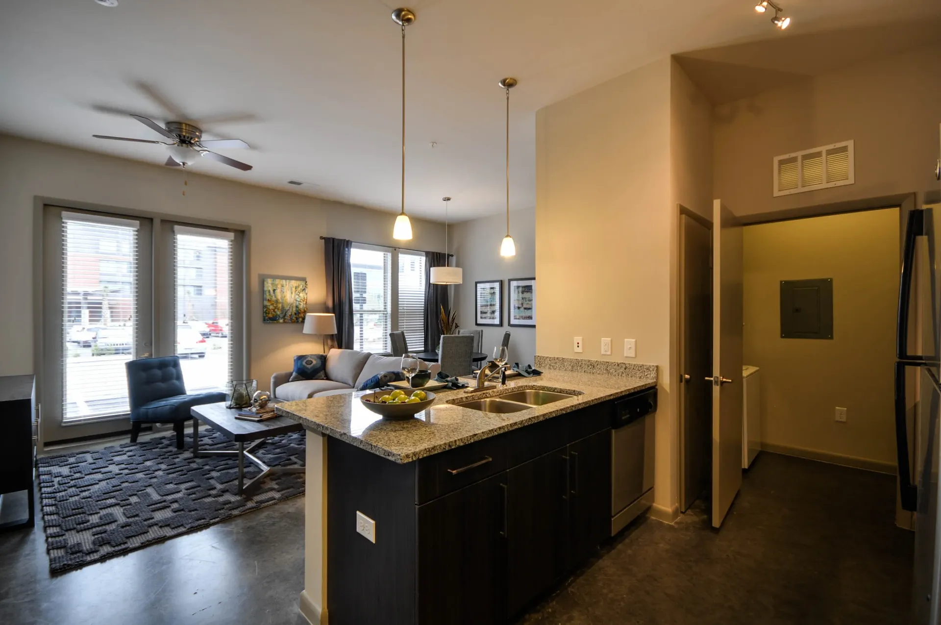 Modern kitchen and living area with island, granite countertops, and stainless steel appliances.