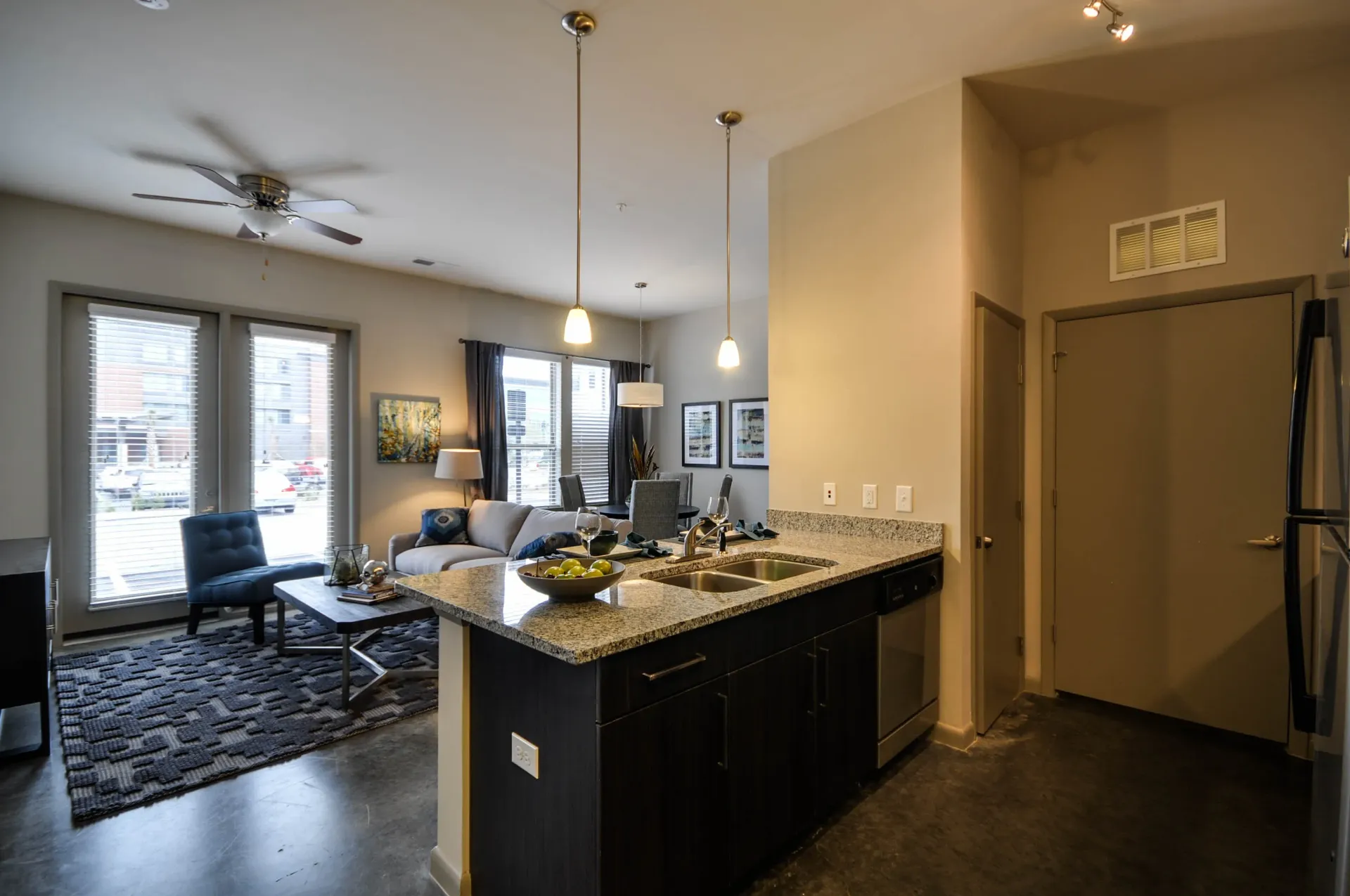 Modern kitchen island with granite countertops and stainless steel appliances, open to living room.
