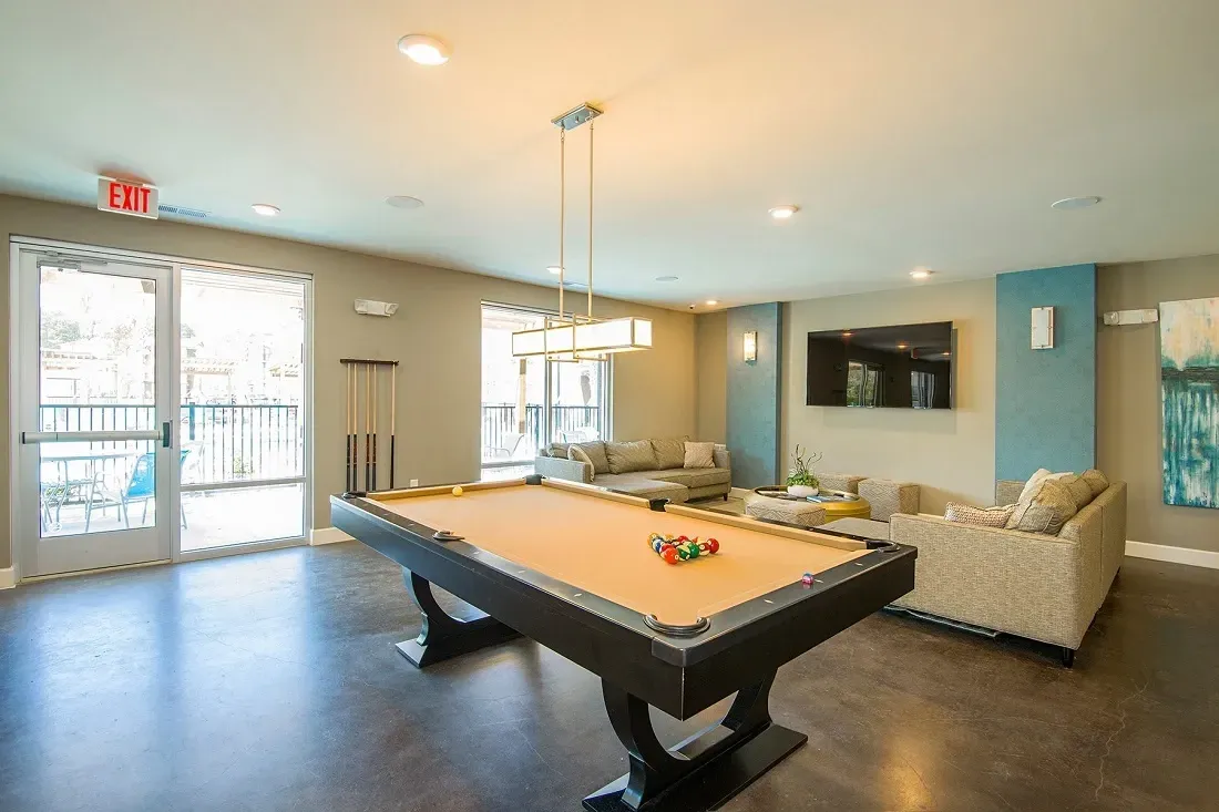 Billiard room with a pool table, seating area, and television.