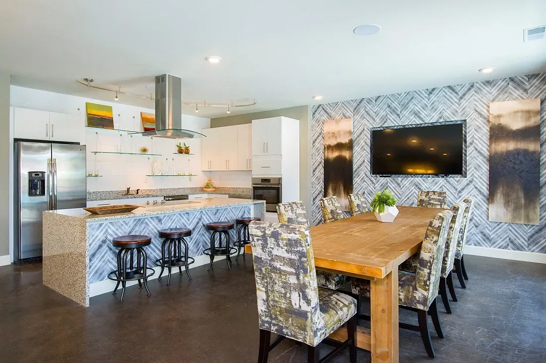 Modern kitchen island with granite countertop and bar stools, adjacent to a dining table with chairs.