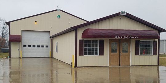 Company Building Small beige industrial building with maroon trim, garage door, and wet pavement outside