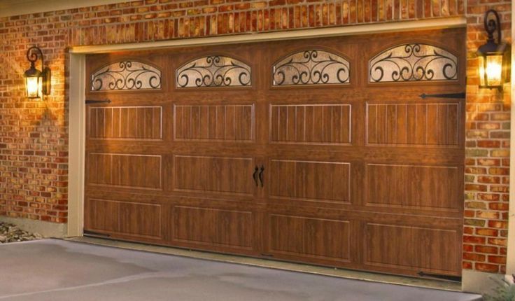 Wooden garage door with decorative arched windows on a brick house facade