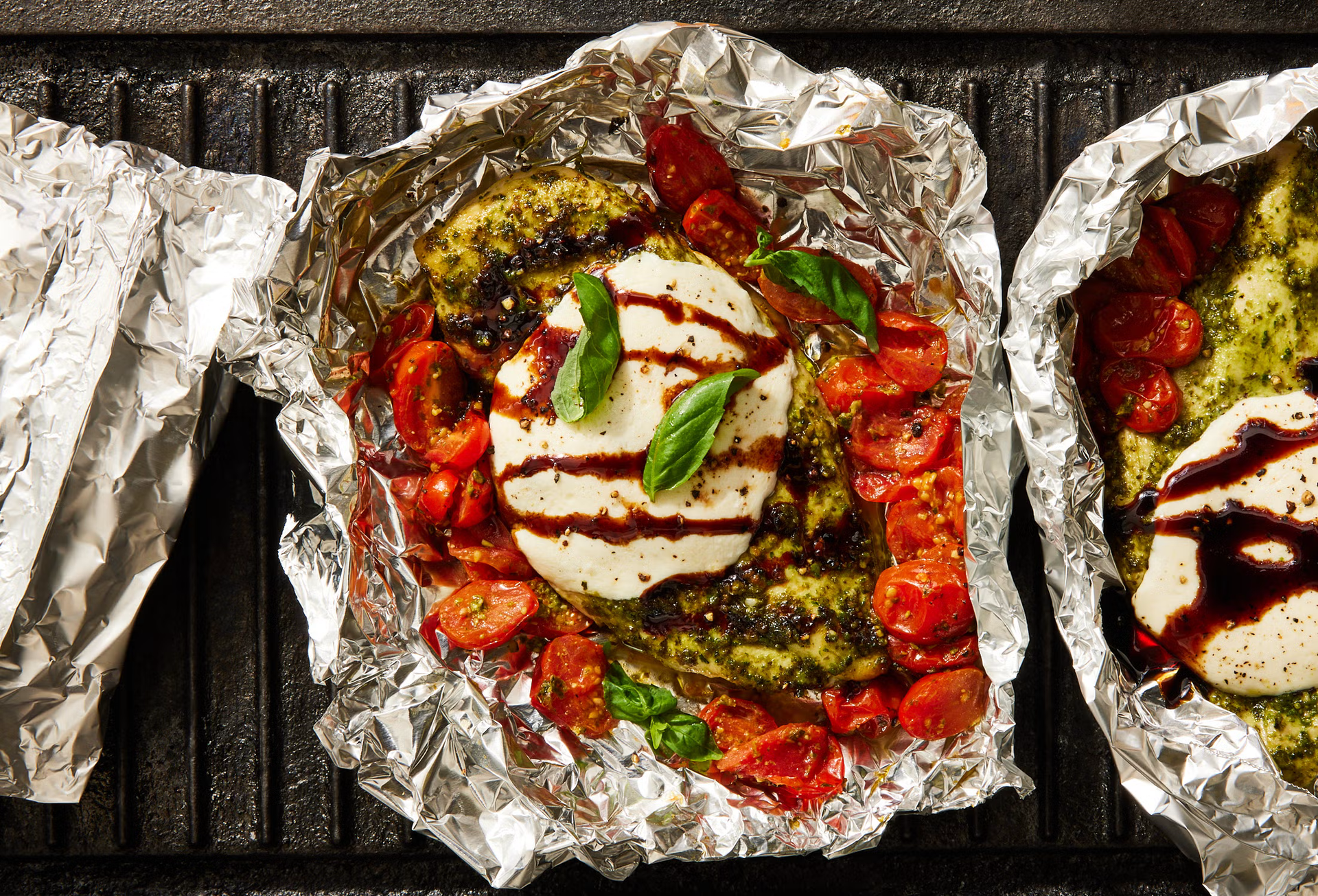 Foil-wrapped stuffed vegetables with tomato sauce and cheese on a grill