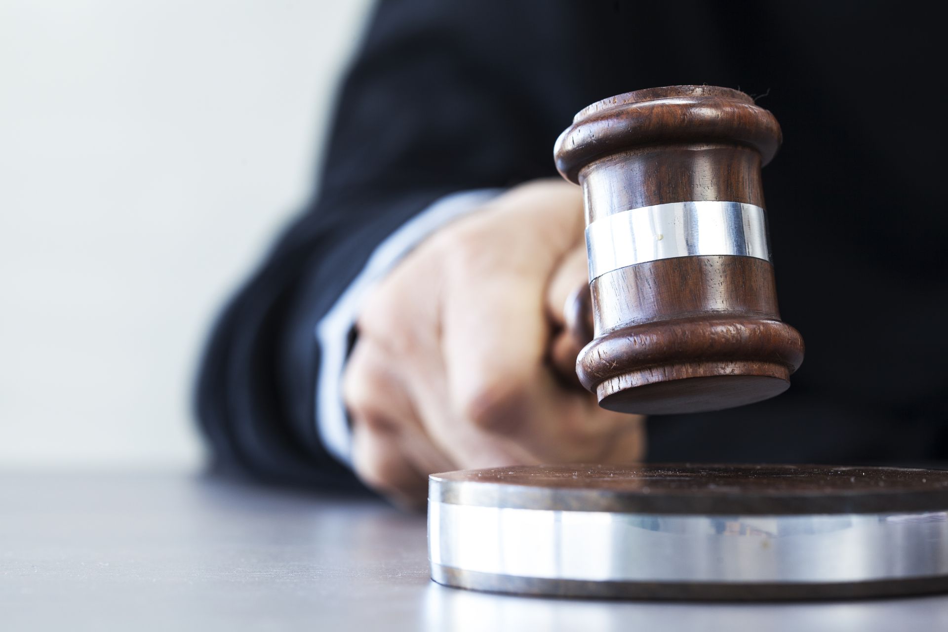 A judge is holding a wooden gavel in his hand.