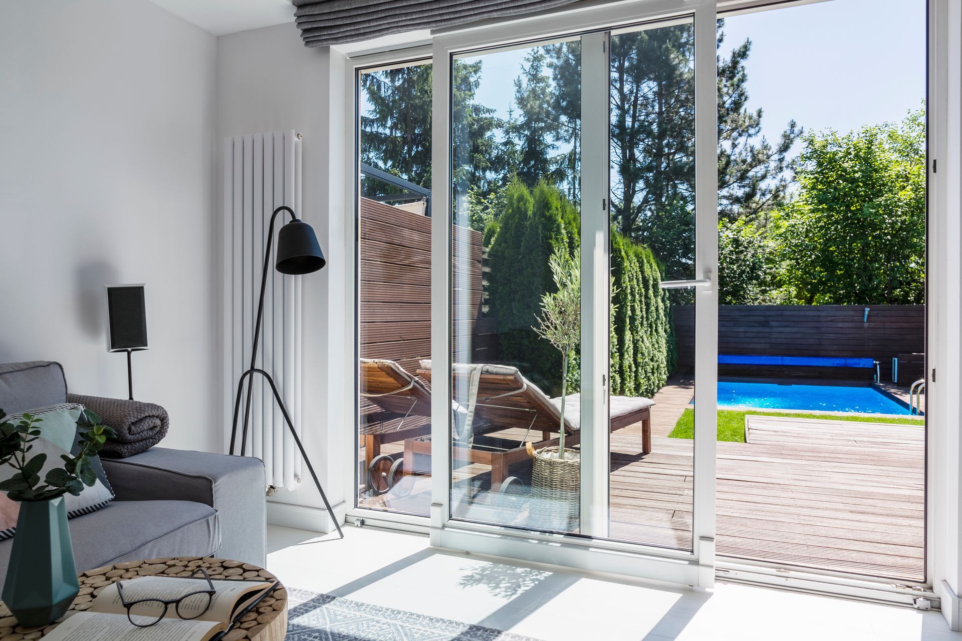 Salon lumineux avec portes vitrées ouvertes donnant sur une piscine dans l'arrière-cour.