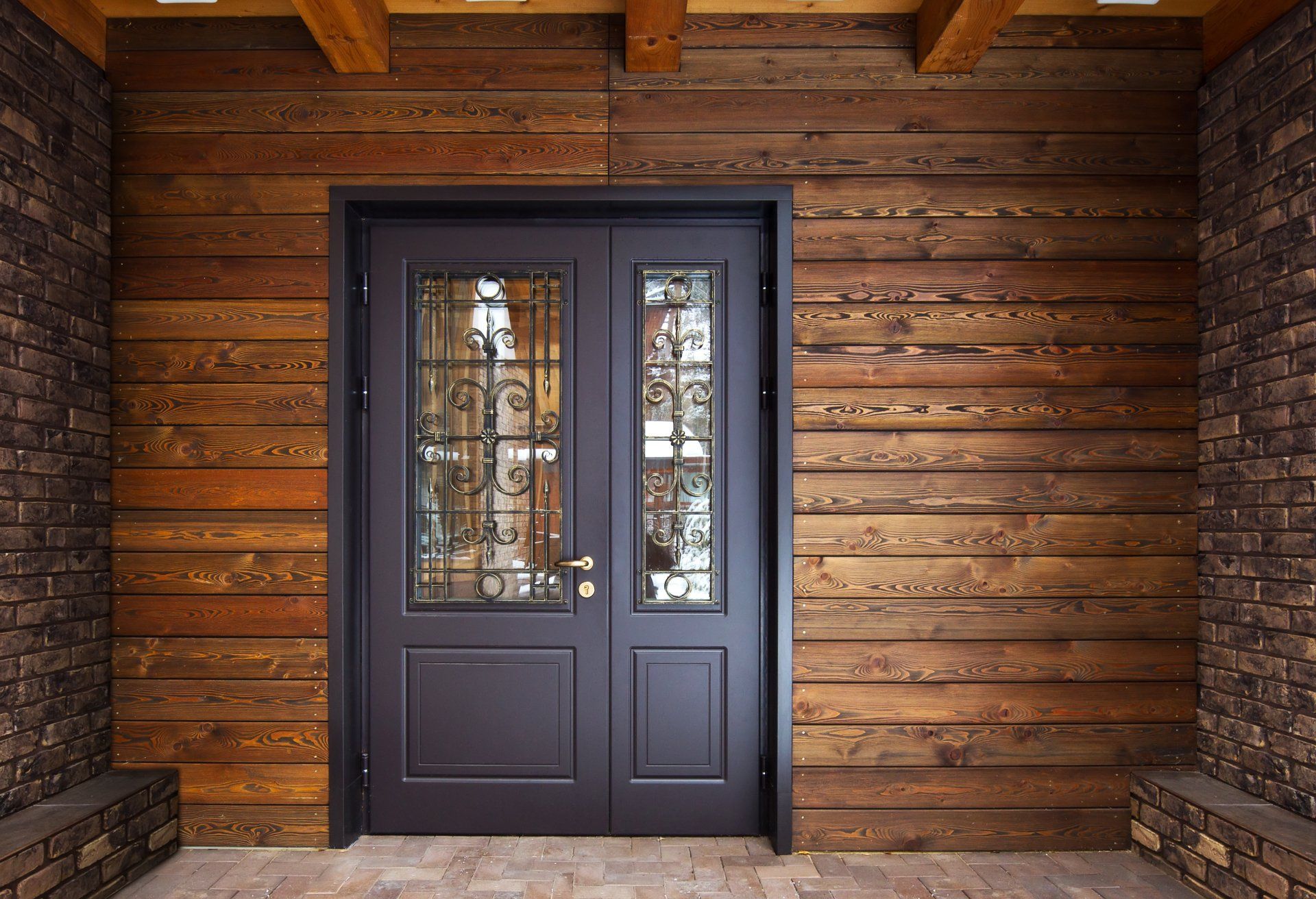 Un mur en bois avec une porte noire et un mur de briques derrière.