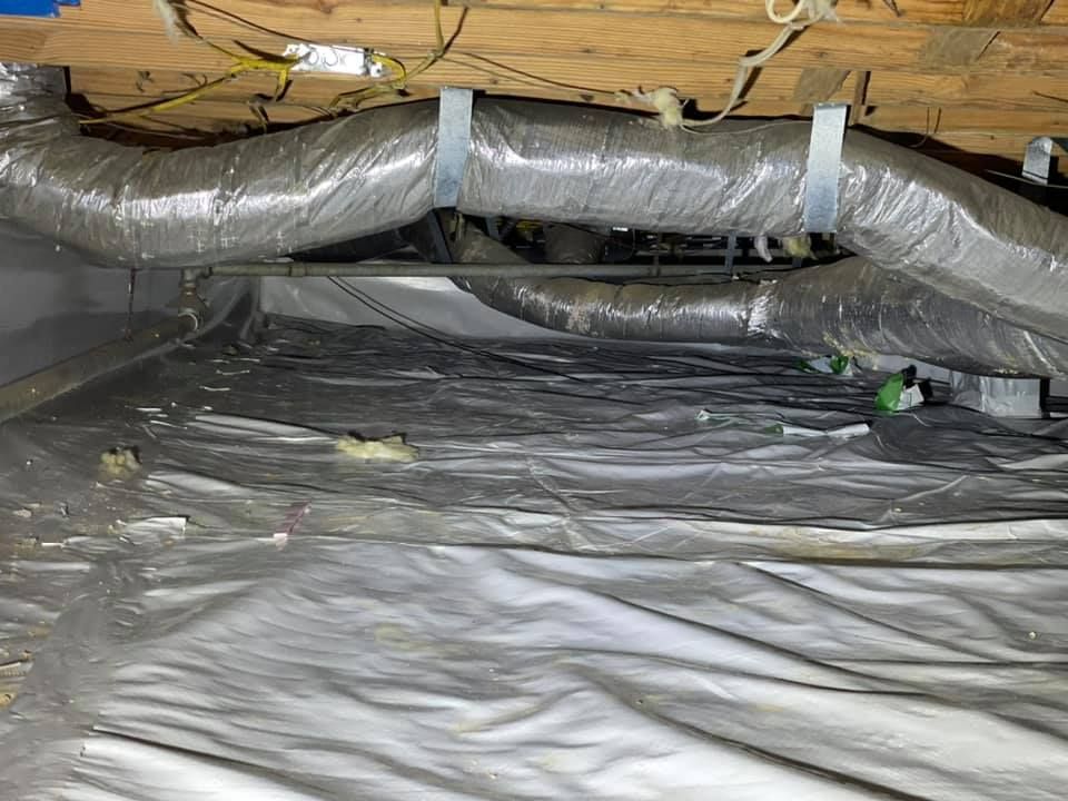 A crawl space filled with plastic and ducts.