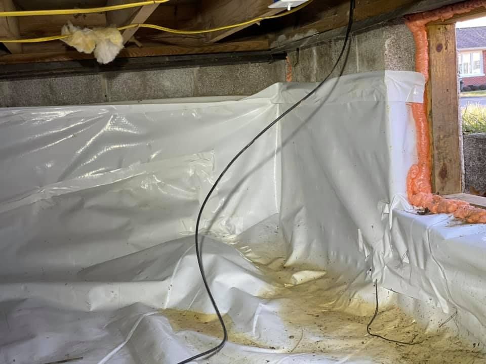 A basement with a lot of plastic covering it and a window.