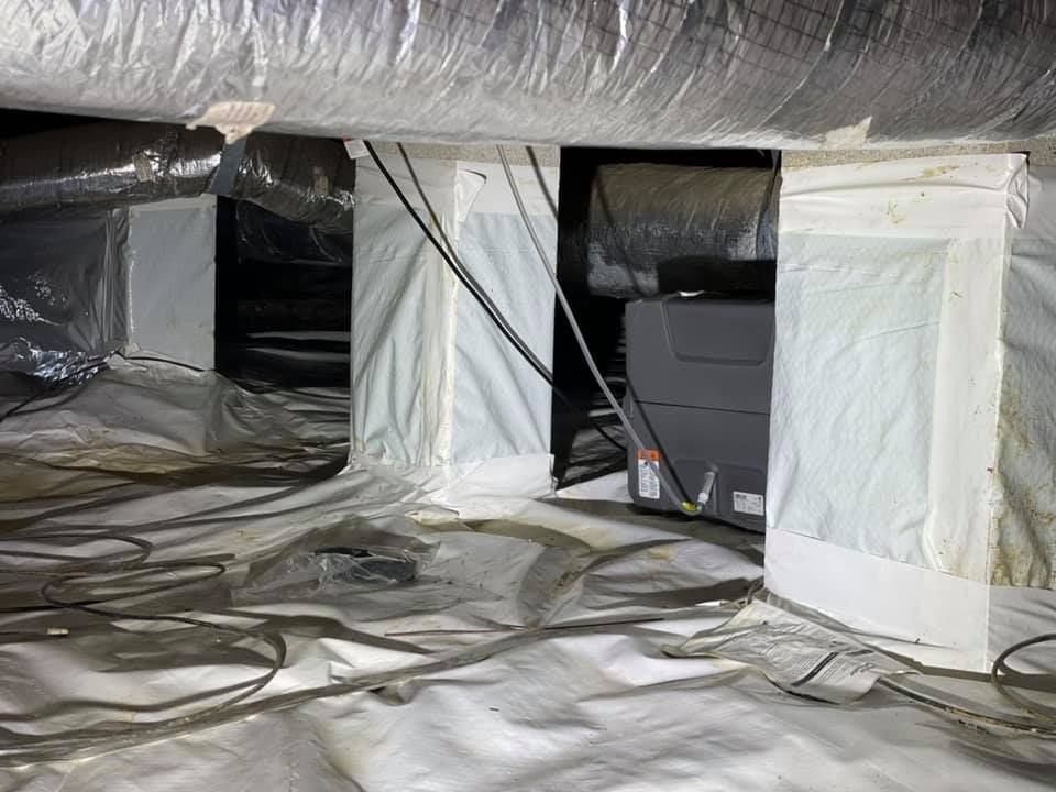 A crawl space with a lot of ducts and wires.
