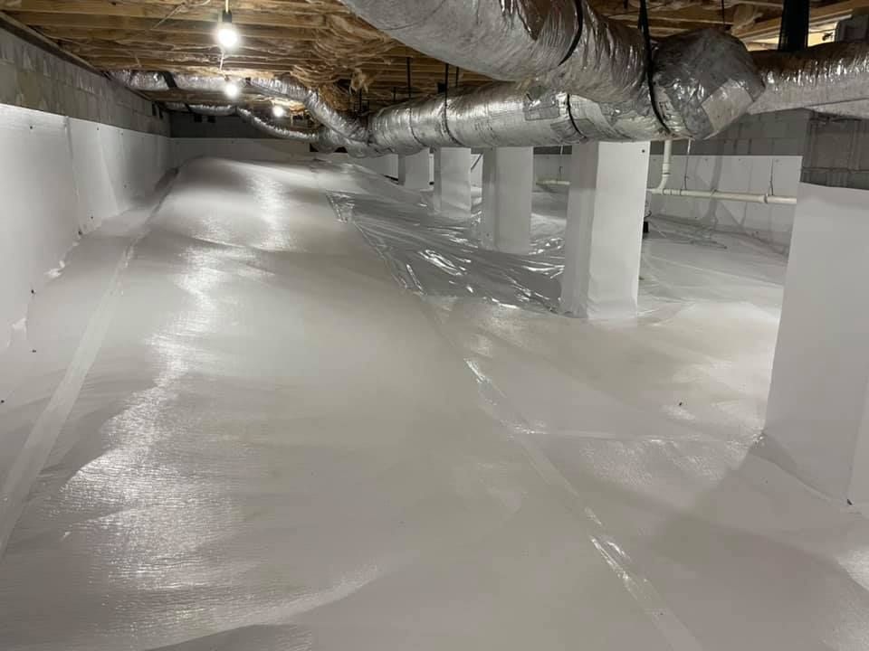 A basement filled with white foam and ducts.