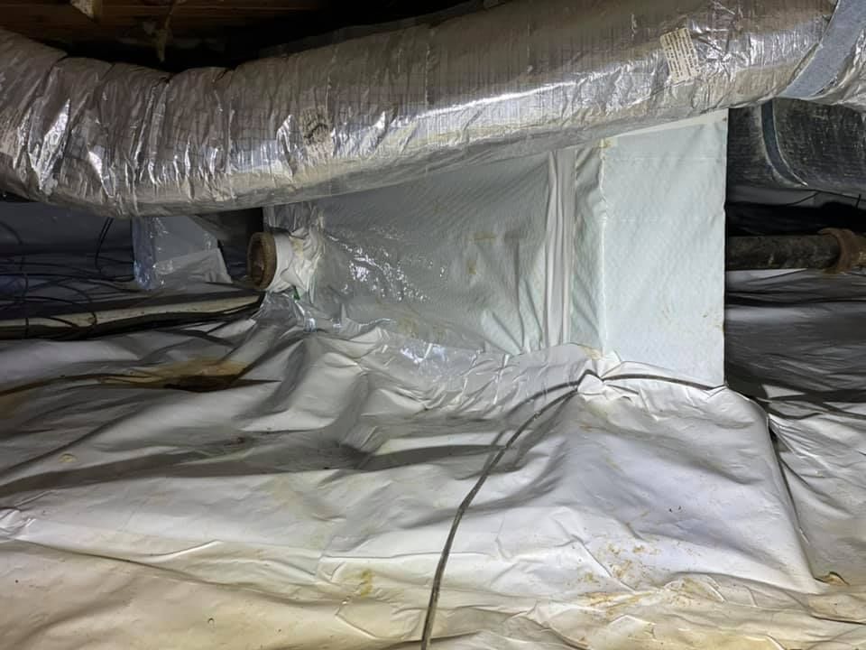 A crawl space filled with plastic and ducts.