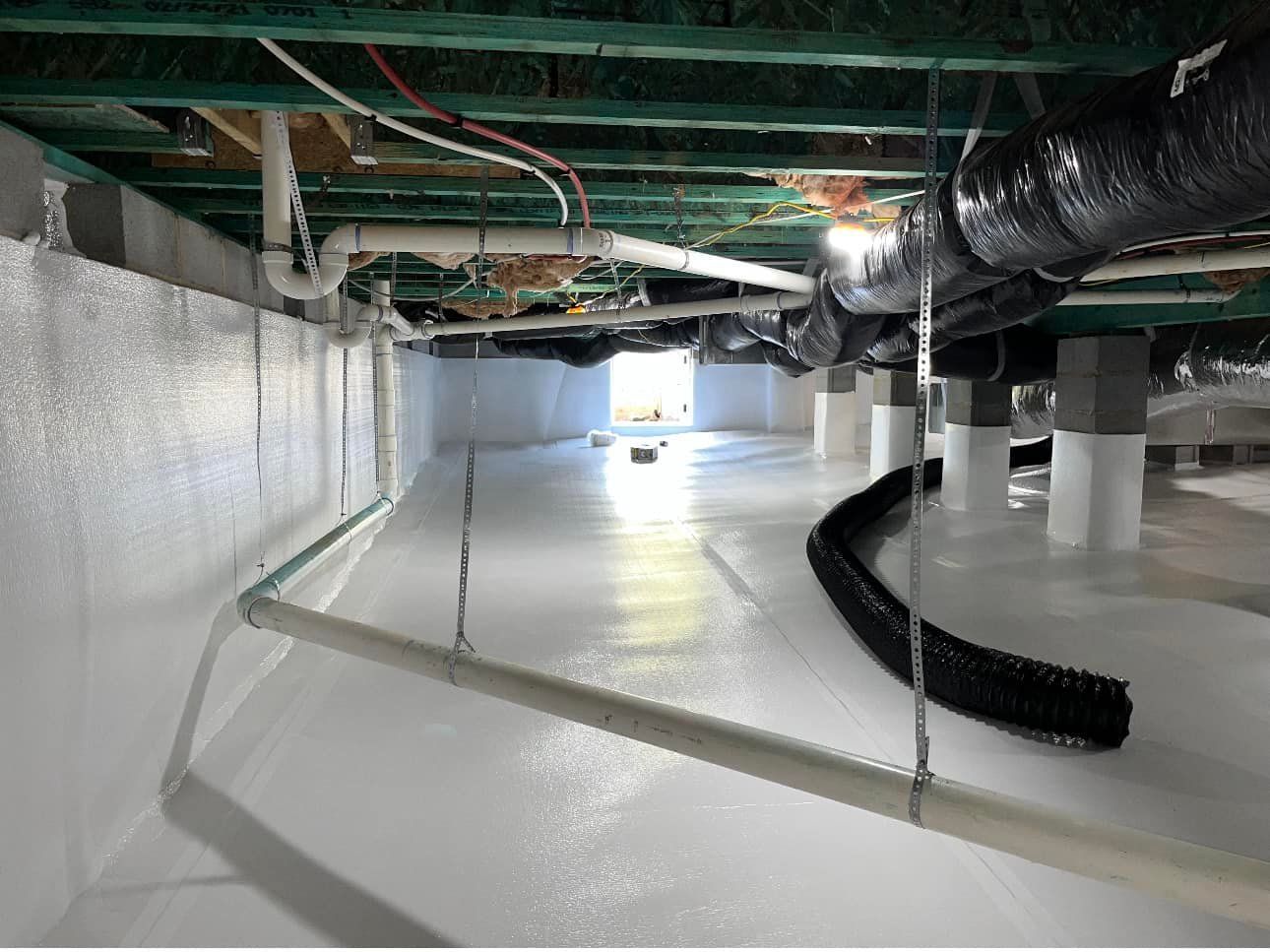 A basement with a lot of pipes and wires hanging from the ceiling.