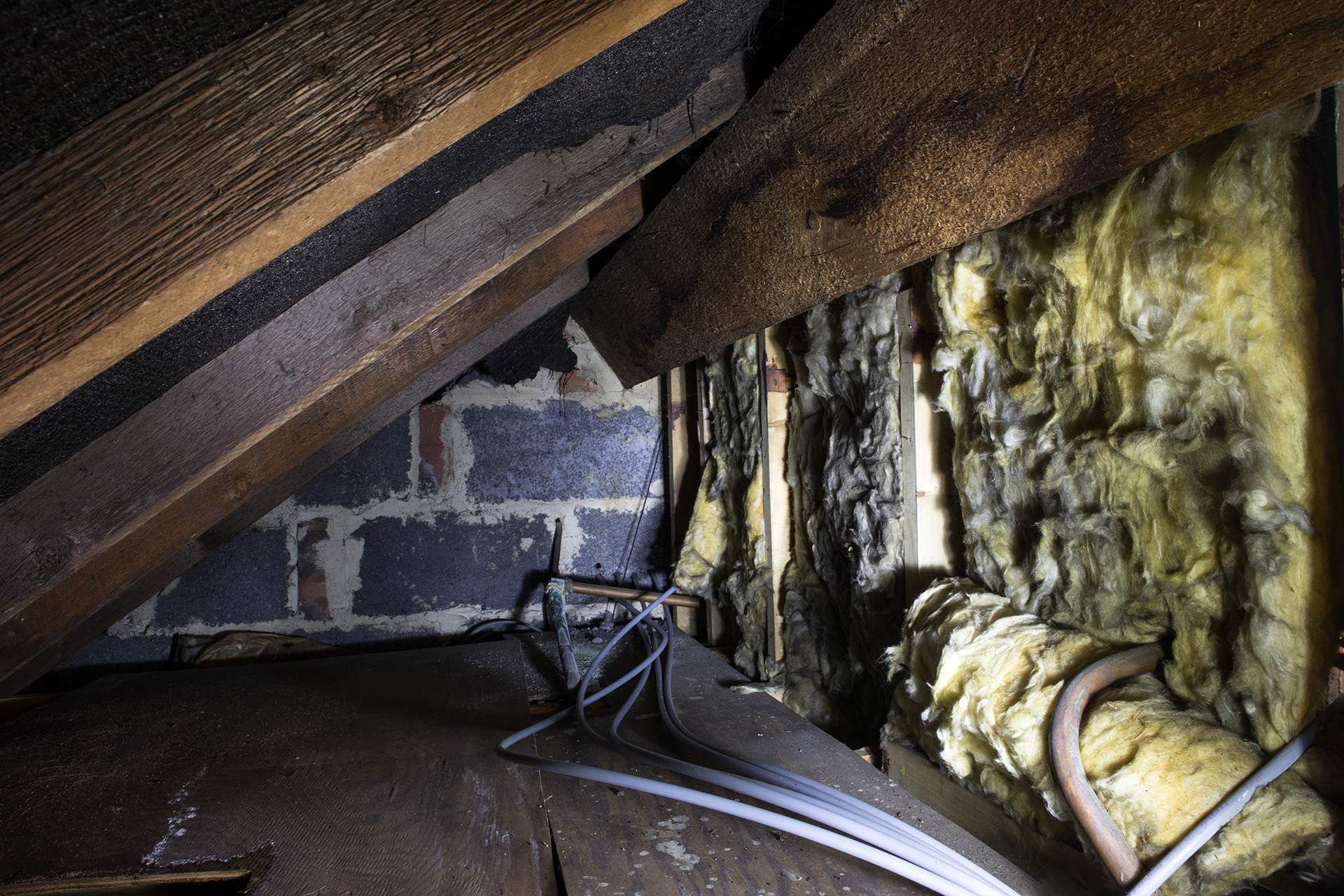 A dark attic with a brick wall and wooden beams.