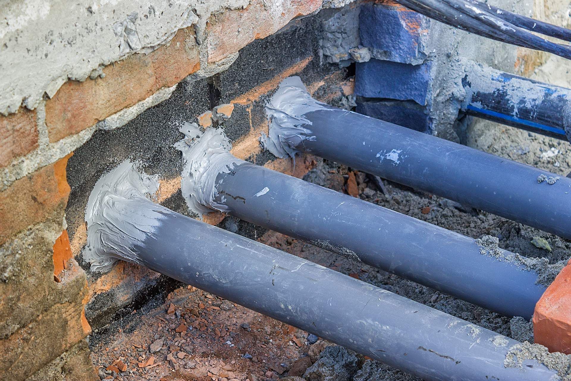 A bunch of pipes are sitting on top of a brick wall.