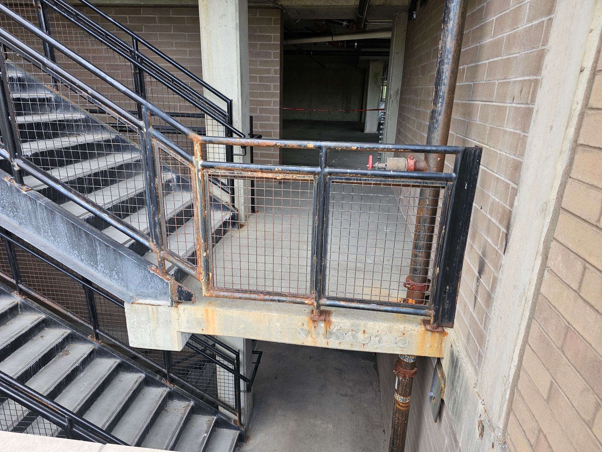Exterior staircase with rusted metal railings and concrete steps.