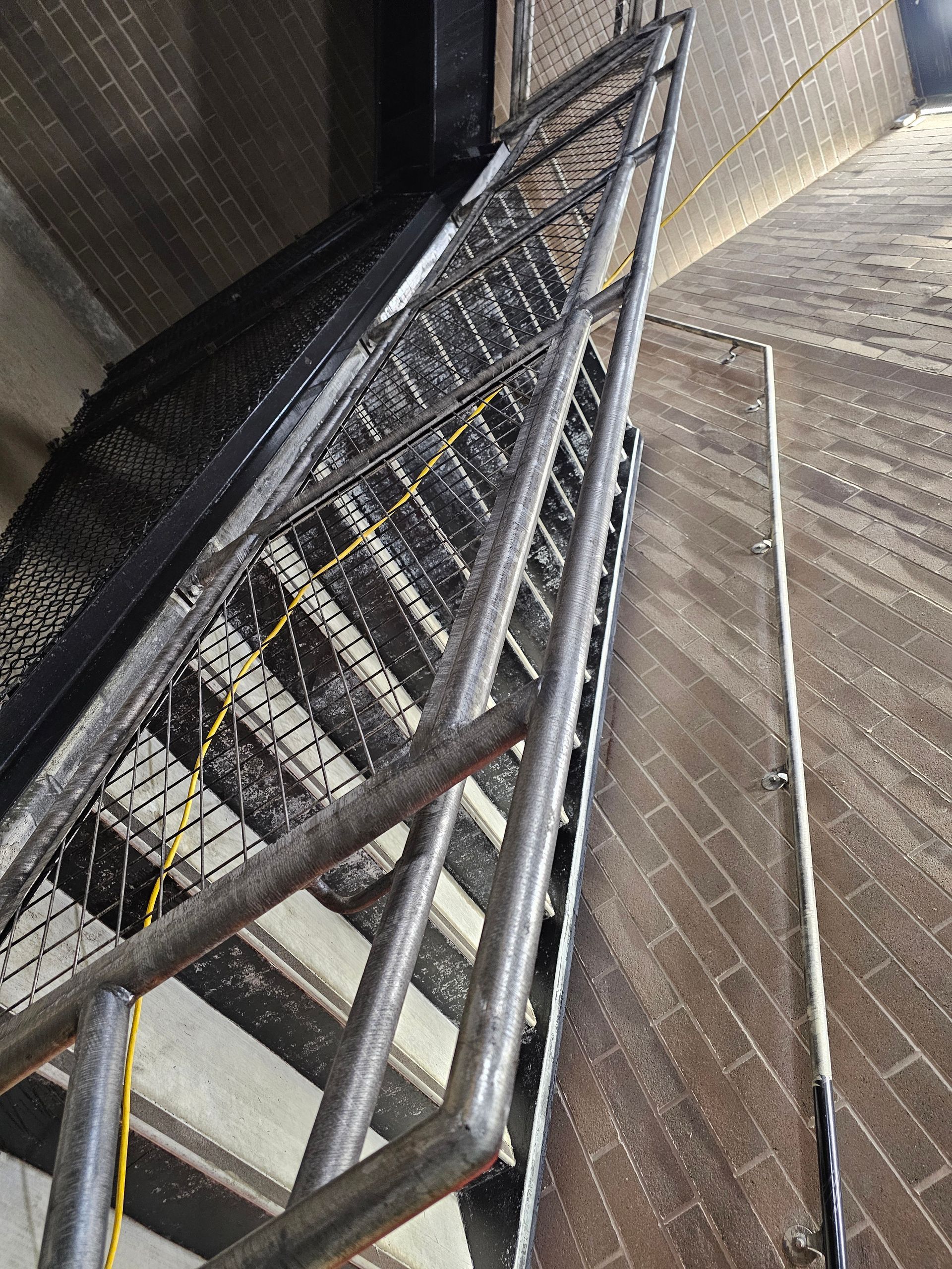 Metal staircase with handrails, inside a brick-lined tower.