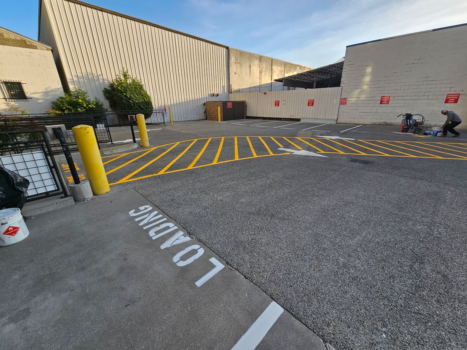 Loading zone with yellow and white lines on asphalt. A worker paints lines.