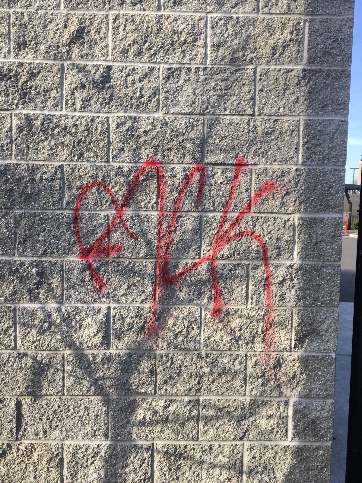 Red graffiti on a gray brick wall, possibly gang-related.