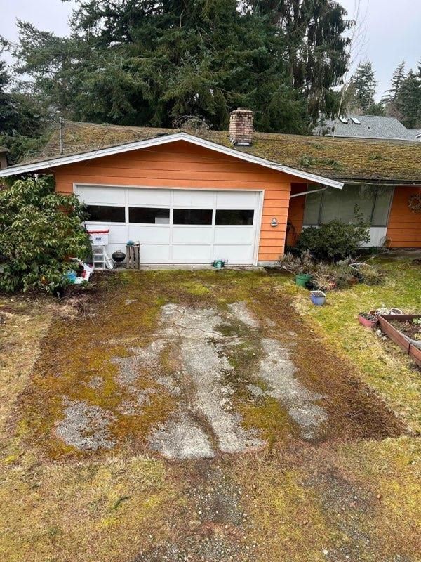 Orange house with mossy driveway and green roof.